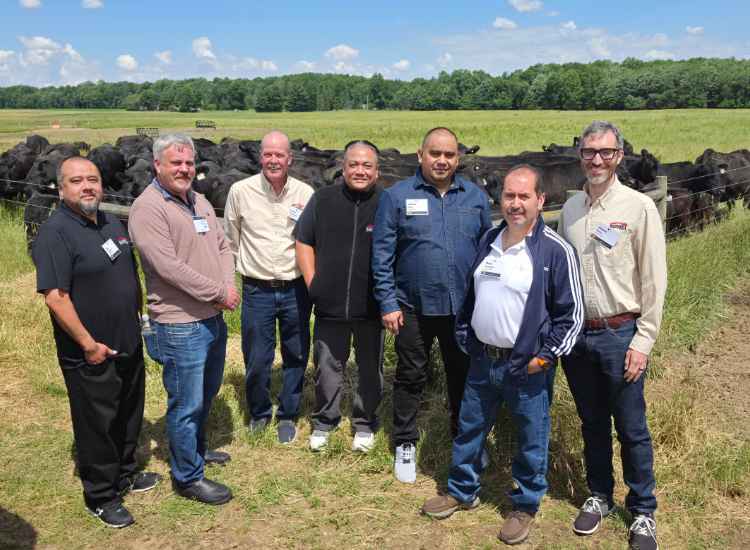 Sunset Foods team and ranchers stand together in an Ohio pasture with Certified Angus Beef cattle grazing behind them.